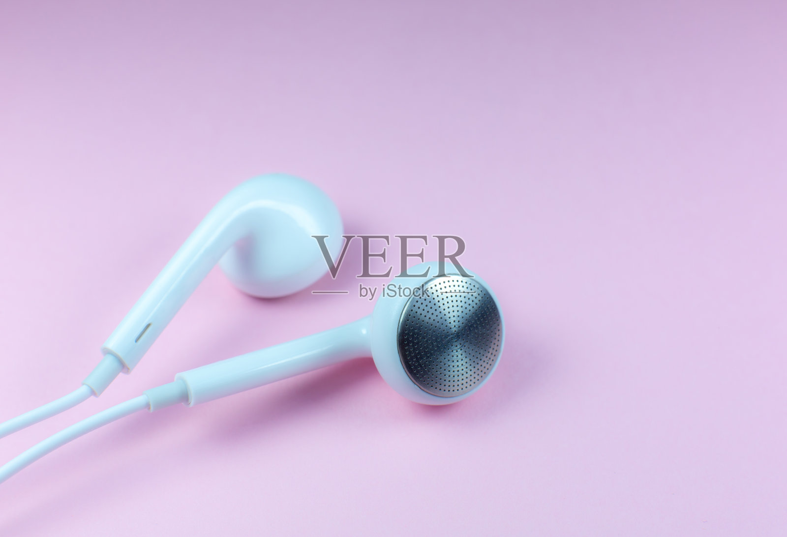 白色耳机躺在粉红色的背景上。现代音乐的概念。音频技术。近距离的照片。照片摄影图片