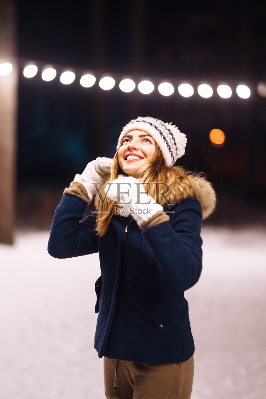 在冬天的森林里，一个快乐的年轻女人手里拿着一个闪闪发光的东西。照片摄影图片