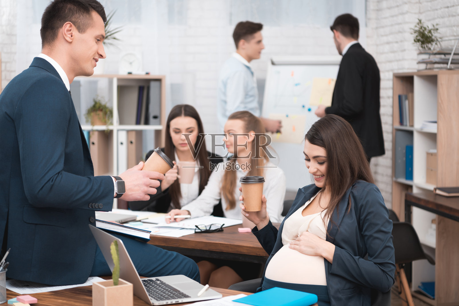 在办公室喝咖啡的女孕妇与她的领导、同事照片摄影图片