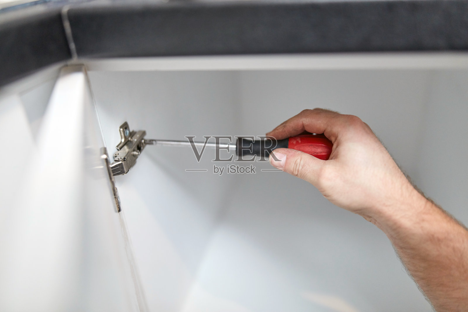 用螺丝刀做门铰链的杂工。照片摄影图片