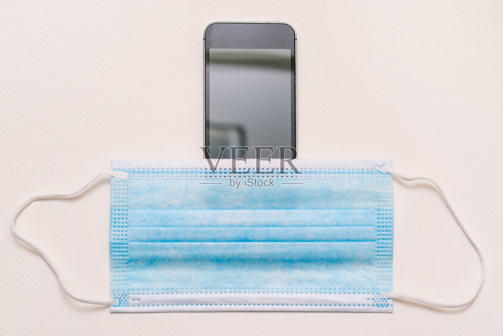 手机和一次性医用口罩。因冠状病毒造成的通信安全。社会距离。医药、保健和技术照片摄影图片