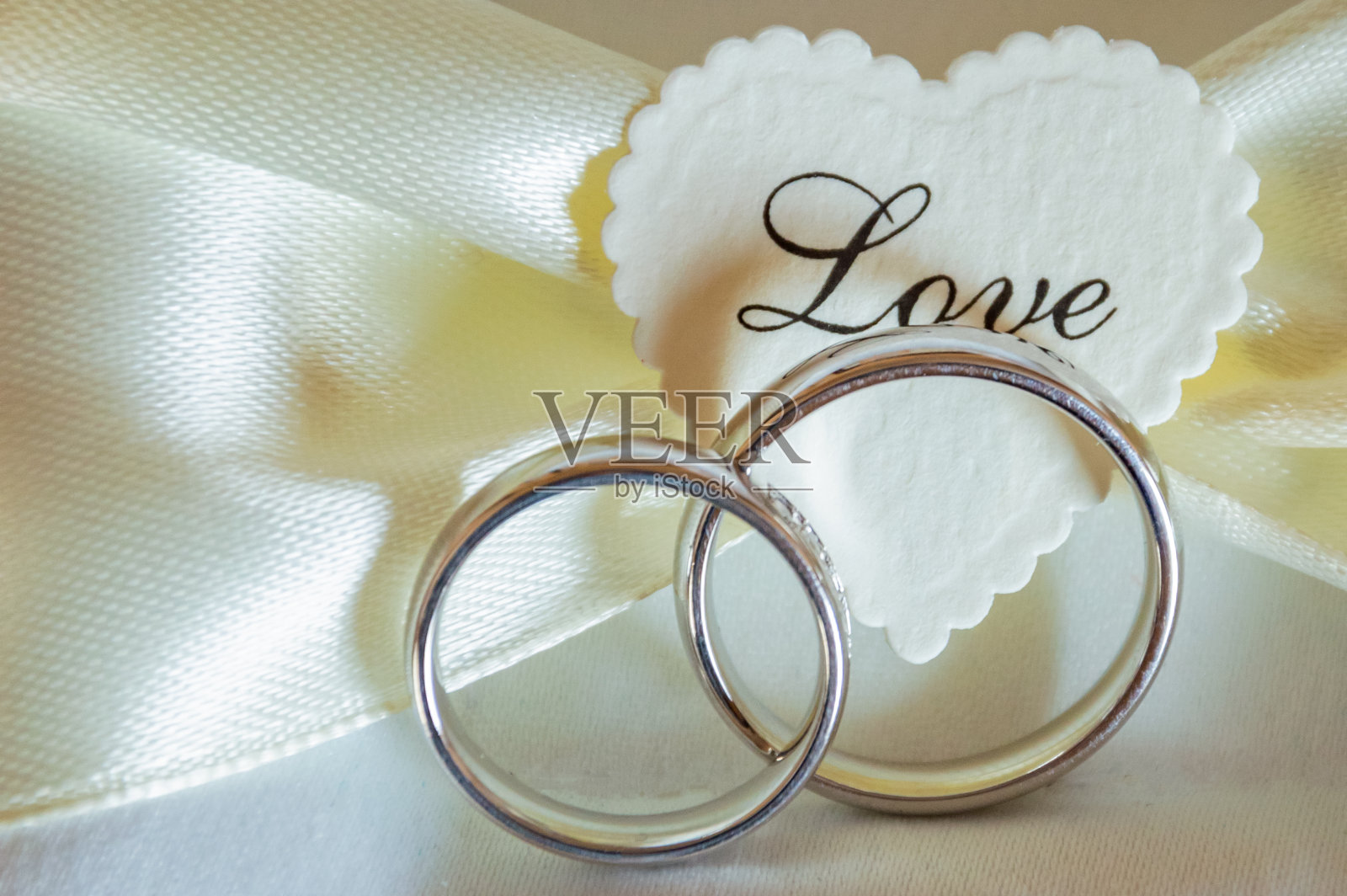 结婚戒指在一个白色的黄金枕头上，上面写着爱照片摄影图片