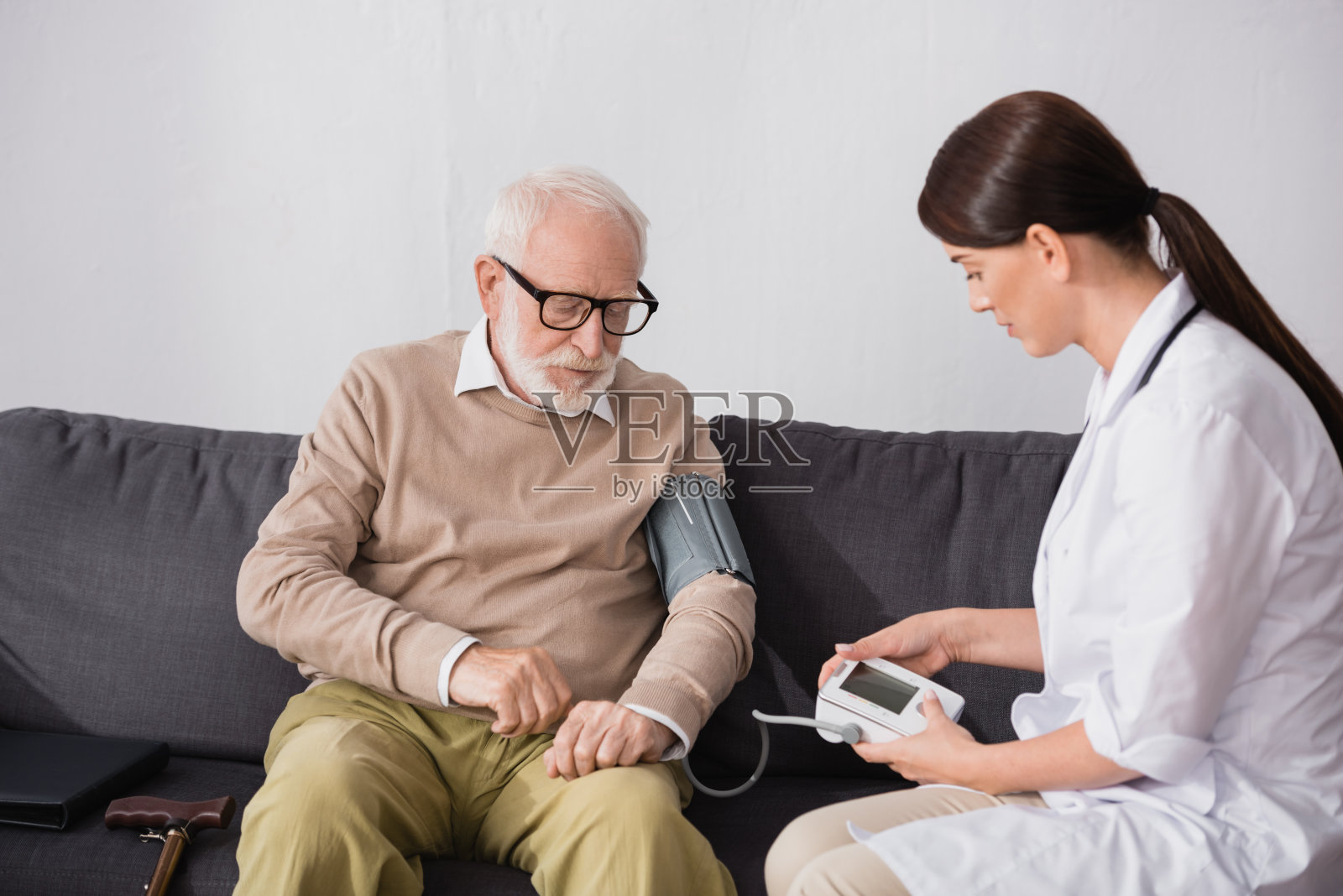 黑发老年护士在家用眼压计检查老年男子照片摄影图片