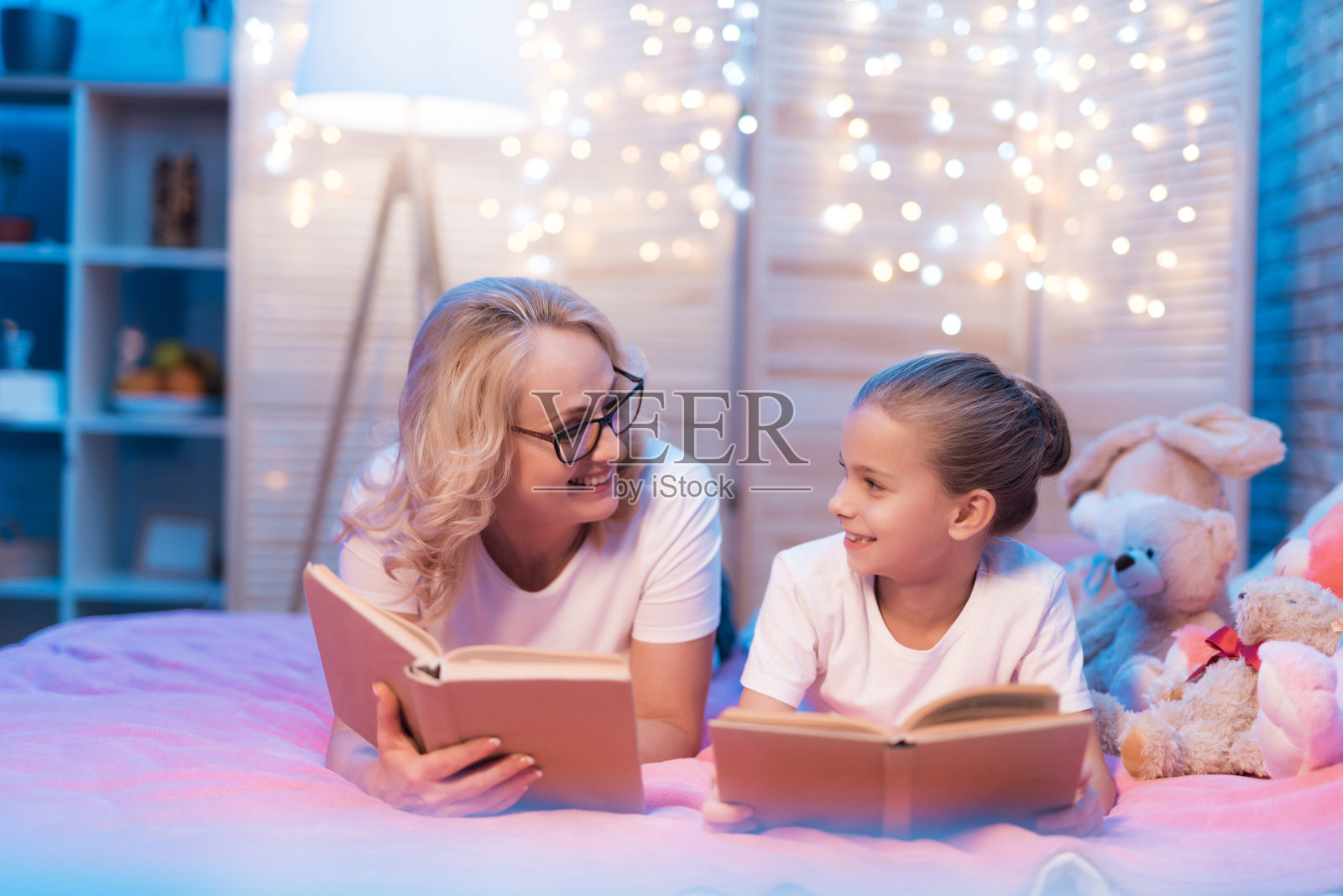 奶奶和孙女晚上睡觉前在家里看书。照片摄影图片
