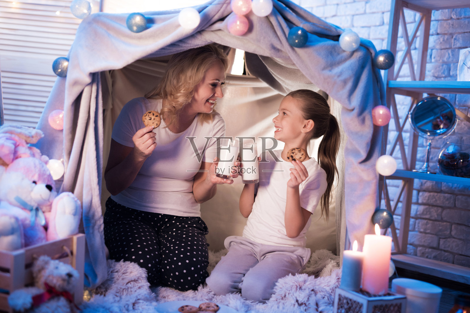 奶奶和孙女晚上在家里的毛毯屋里吃着牛奶饼干。照片摄影图片