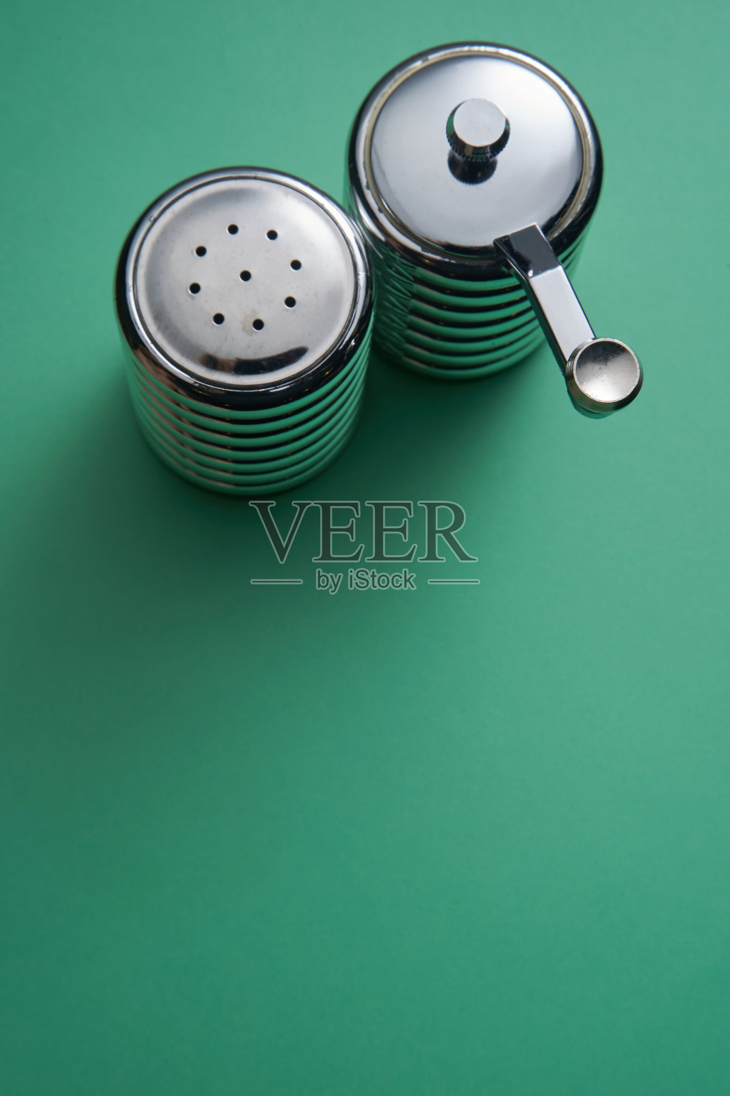 盐和胡椒容器在绿色的背景照片摄影图片