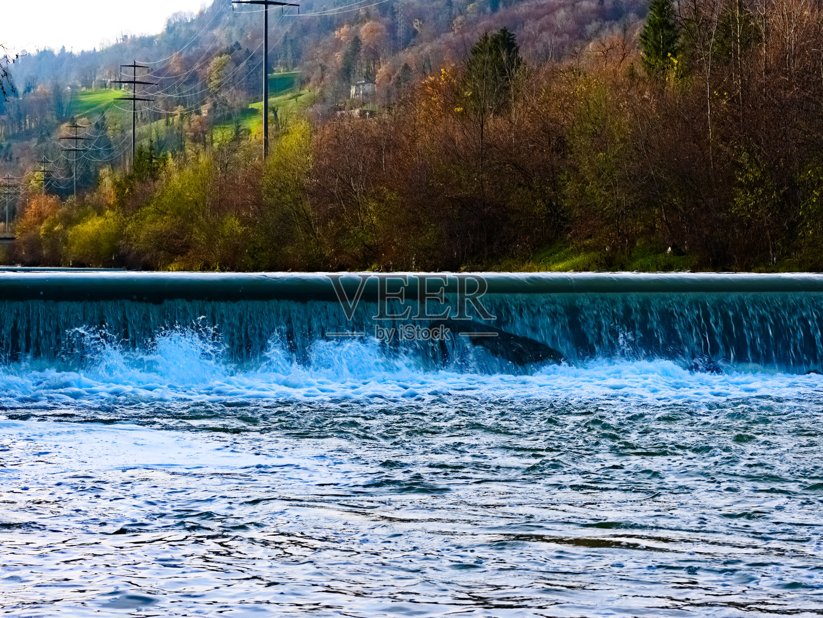 “kleine Emme”河的人工瀑布，这是为防洪而建的。银行区内秋季有森林和架空输电线路。在瑞士卢塞恩地区的麦尔特斯社区附近照片摄影图片