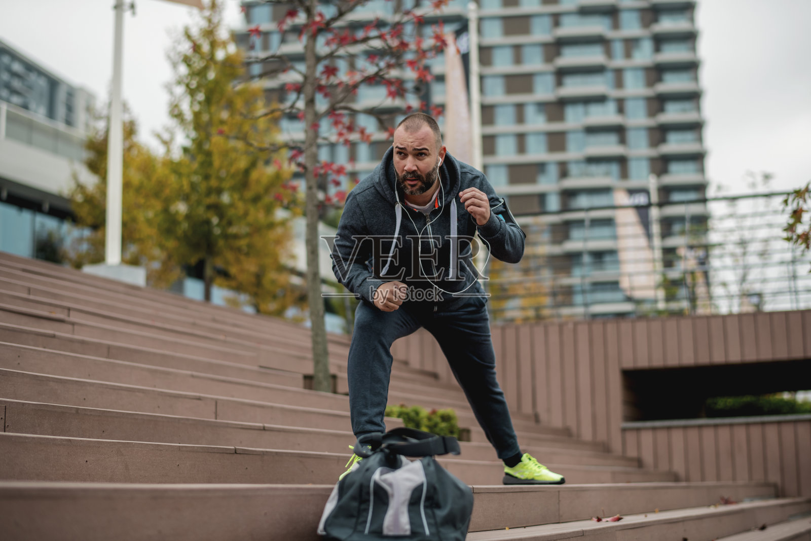 一个留着胡子的年轻人在跑步前伸展。照片摄影图片
