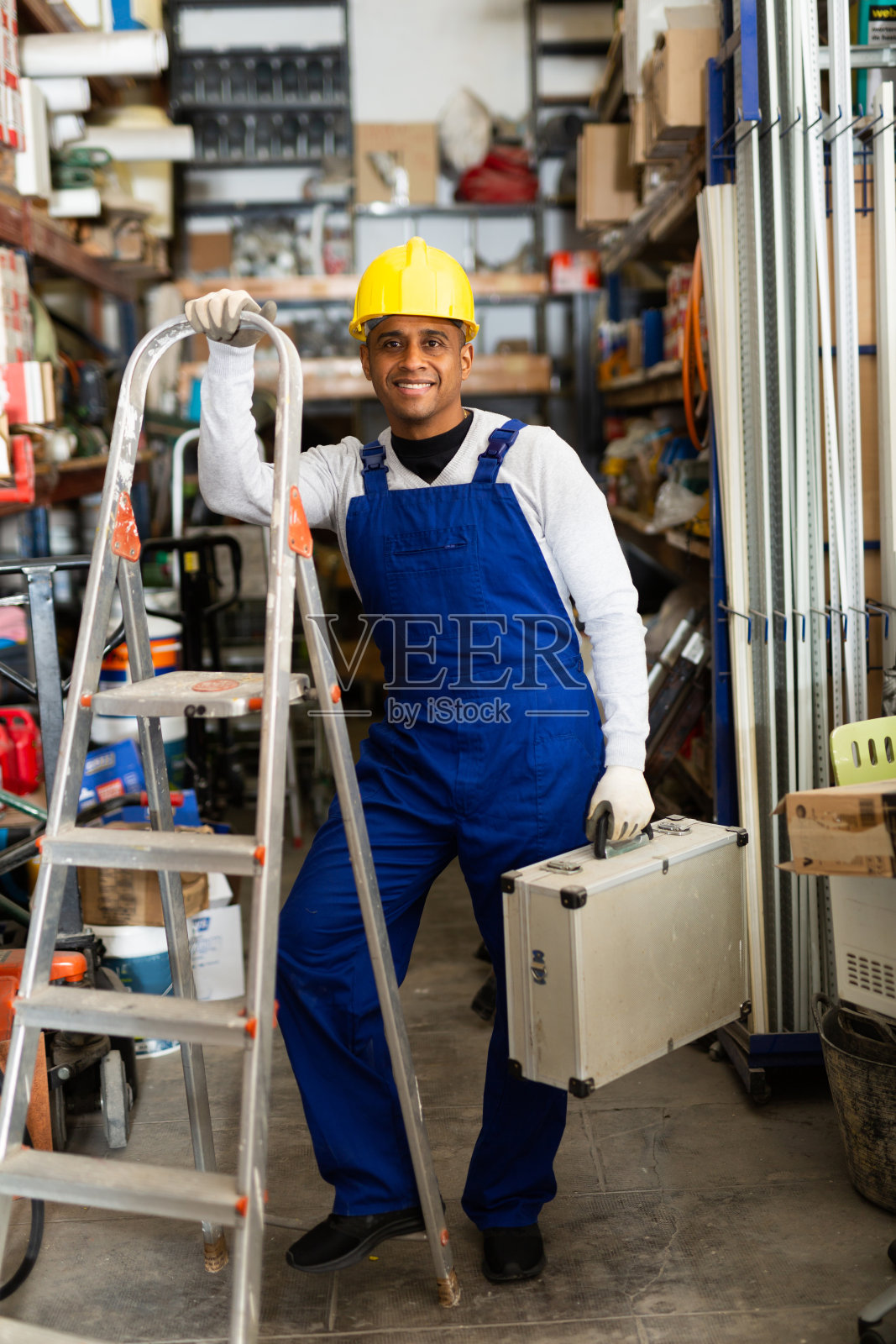 工人的肖像在保护头盔和工装裤工具箱在五金店照片摄影图片