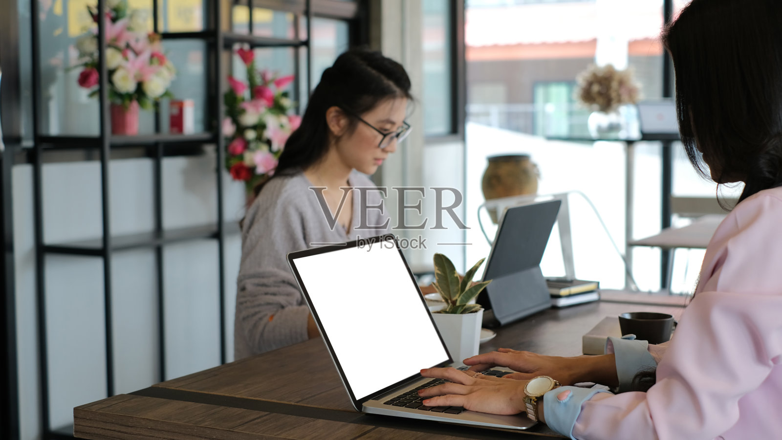 两位女商人正在会议室里用平板电脑讨论新项目。照片摄影图片