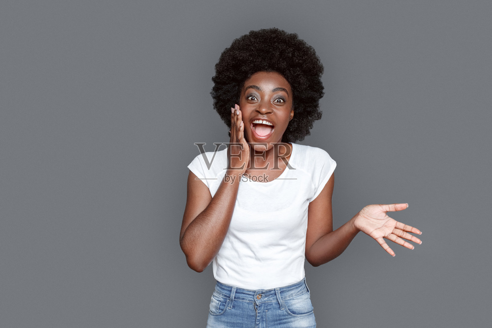 年轻女子孤立地站在灰色的照相机上兴奋地笑着照片摄影图片