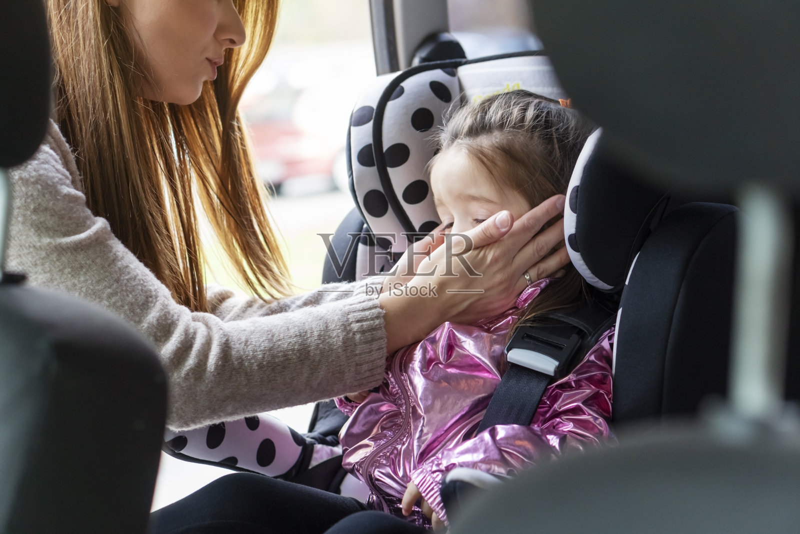 妈妈把孩子放在汽车安全座椅上照片摄影图片