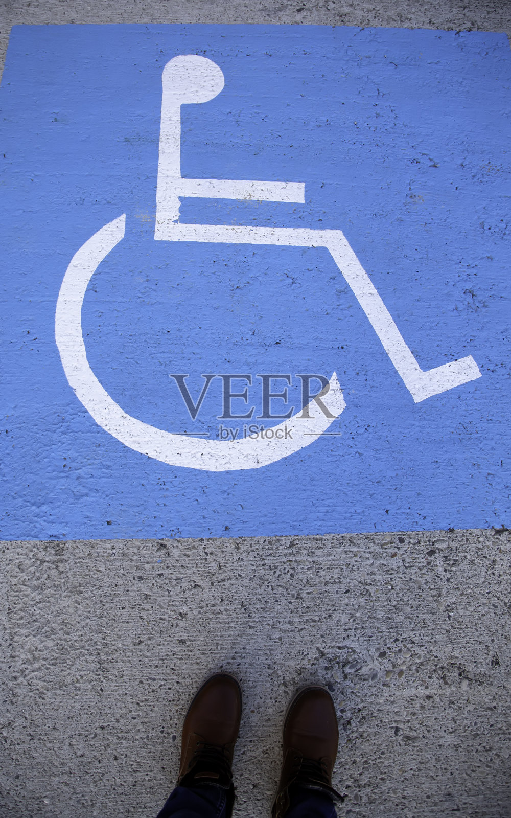 脚踩在柏油路上的残疾人标志上照片摄影图片