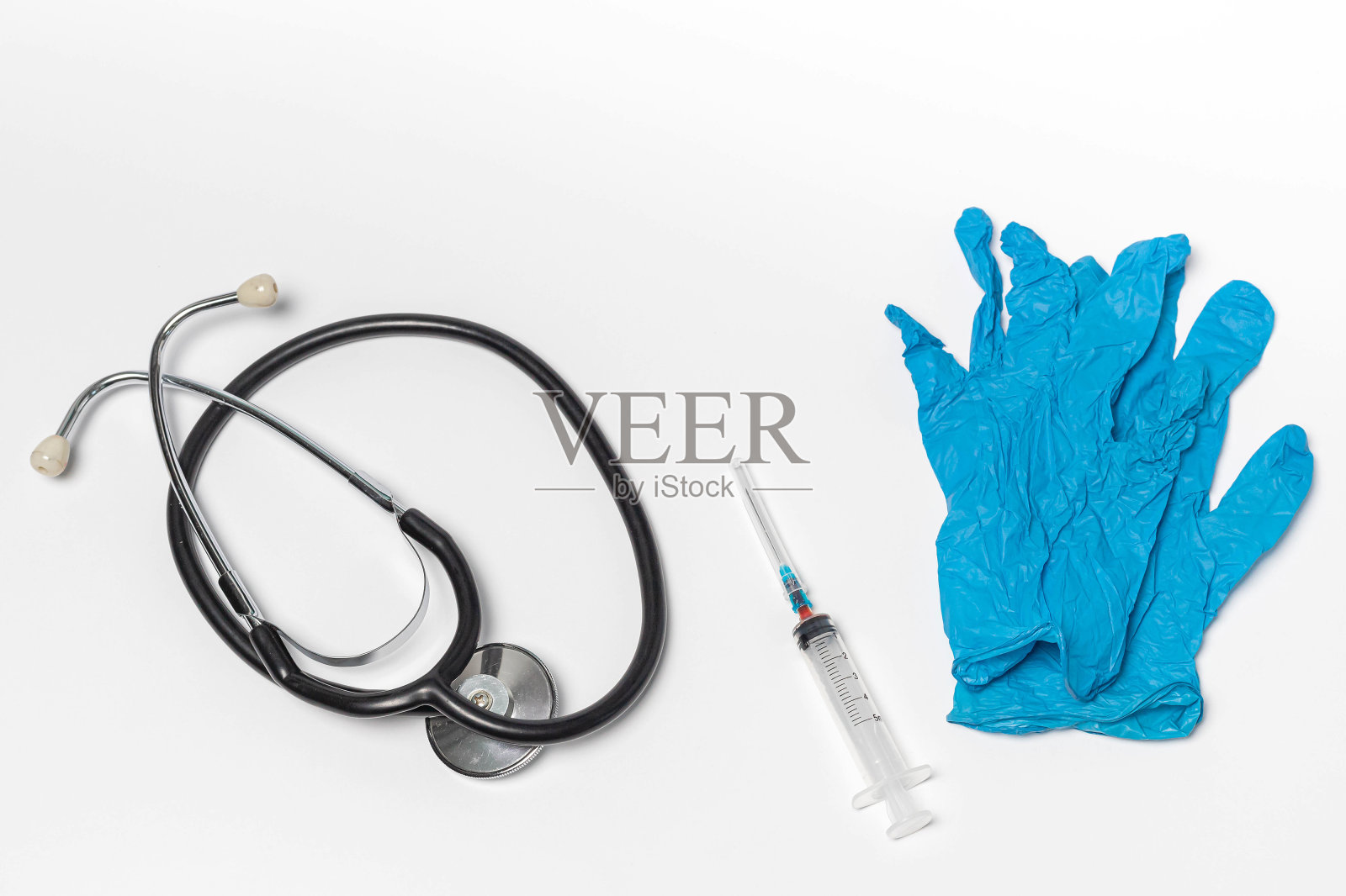 一双蓝色医用手套，听诊器和皮下注射器，白色背景隔离。照片摄影图片