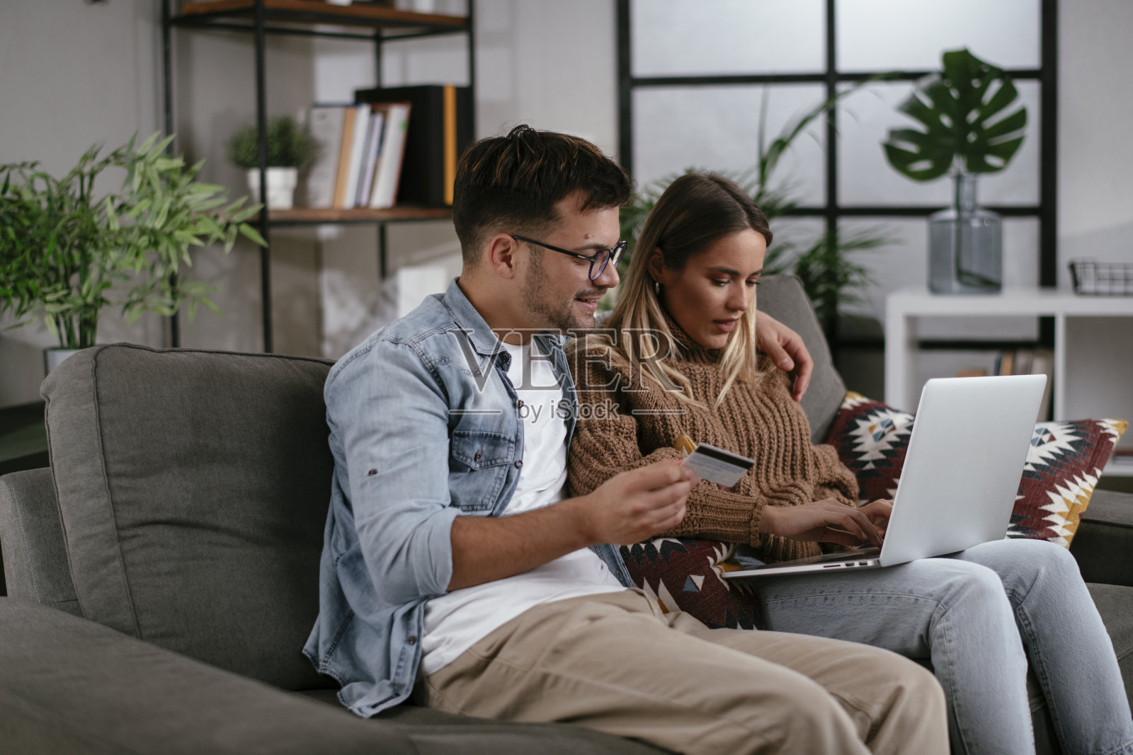 年轻夫妇在家里使用信用卡和笔记本电脑。照片摄影图片