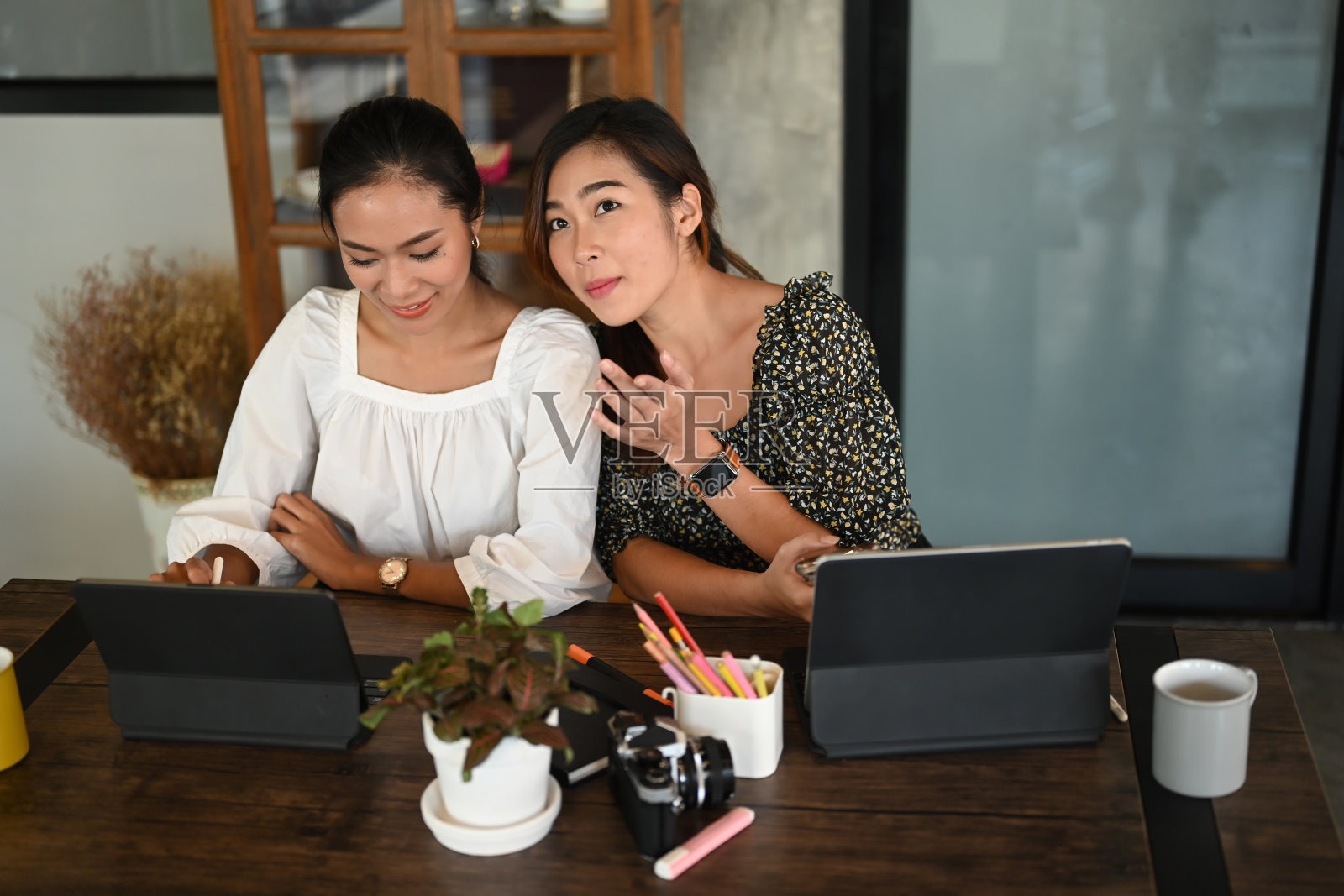 两个女商人坐在现代化的会议室里开着一个非正式的会议。照片摄影图片