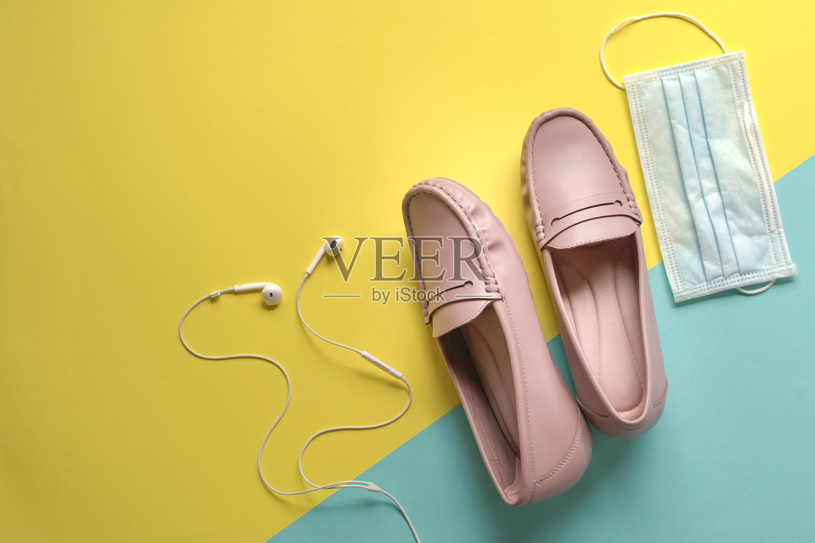 时尚的女鞋，耳机和医用口罩黄色和蓝色背景。照片摄影图片