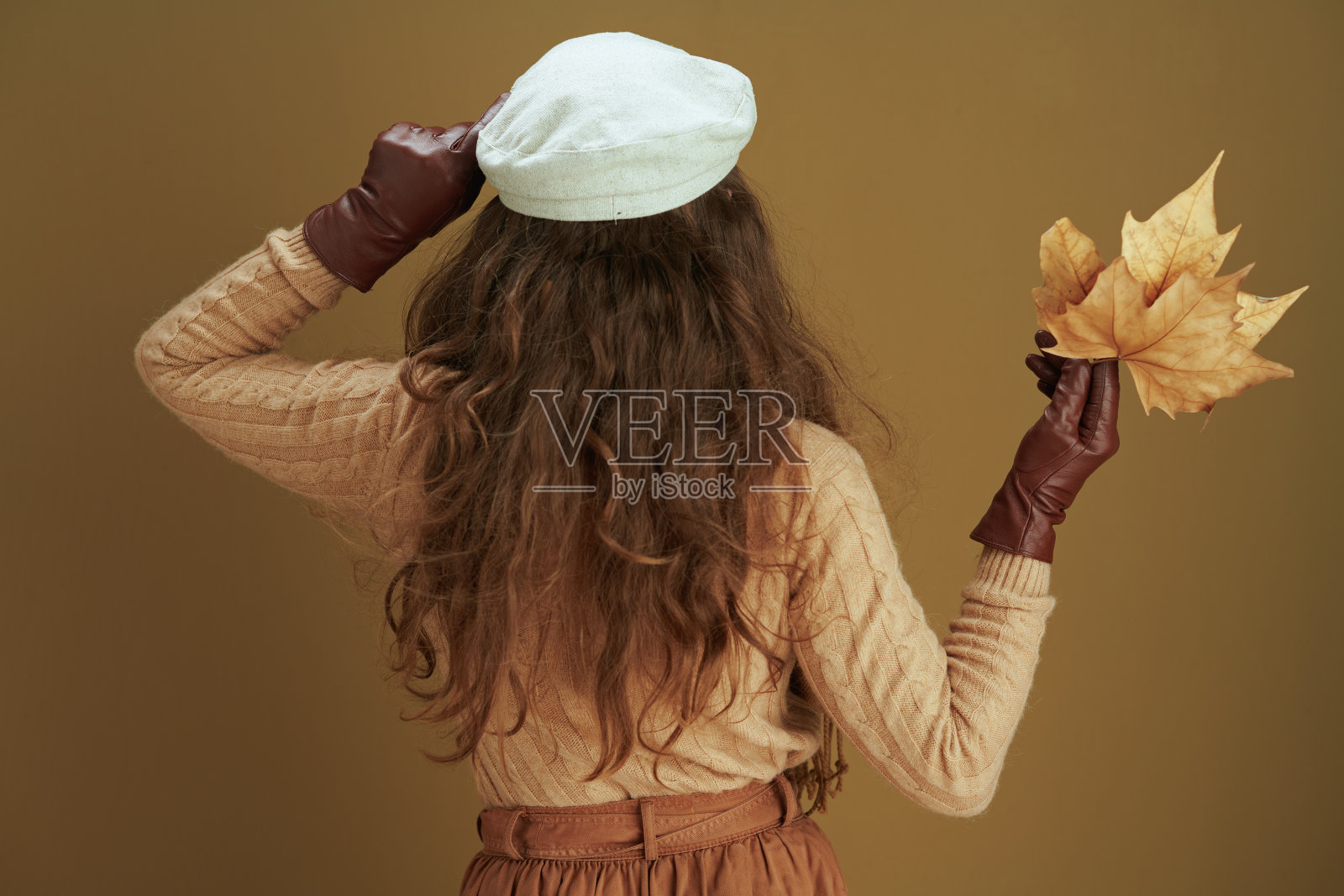 从后面看，穿着毛衣的家庭主妇以青铜色为背景照片摄影图片