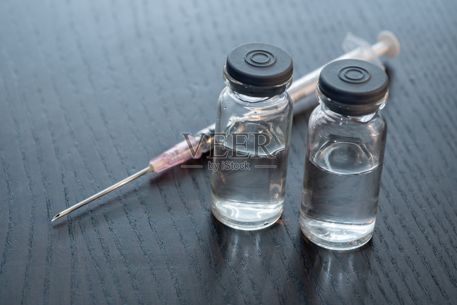 疫苗瓶放在木桌上，注射用的。疫苗和免疫概念。照片摄影图片