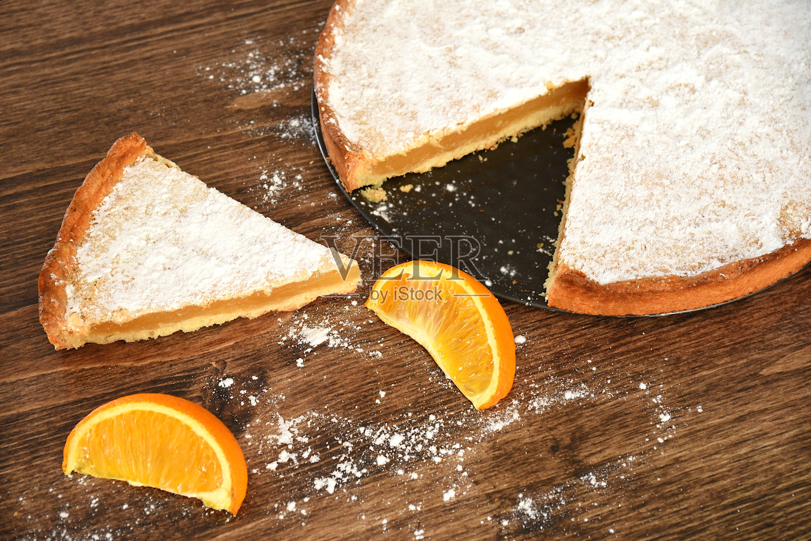 一块自制的柠檬和橘子馅的派，上面覆盖着糖粉放在木桌上照片摄影图片