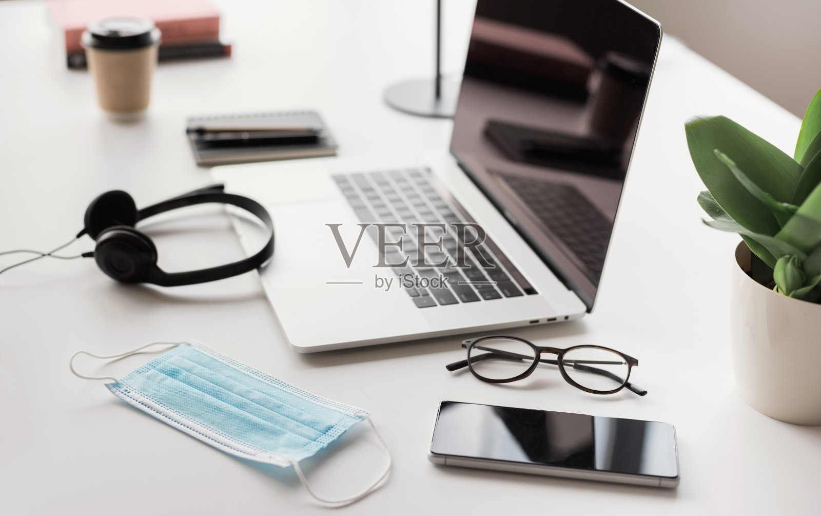 工作的地方。笔记本电脑，耳机，口罩，办公桌上的智能手机照片摄影图片