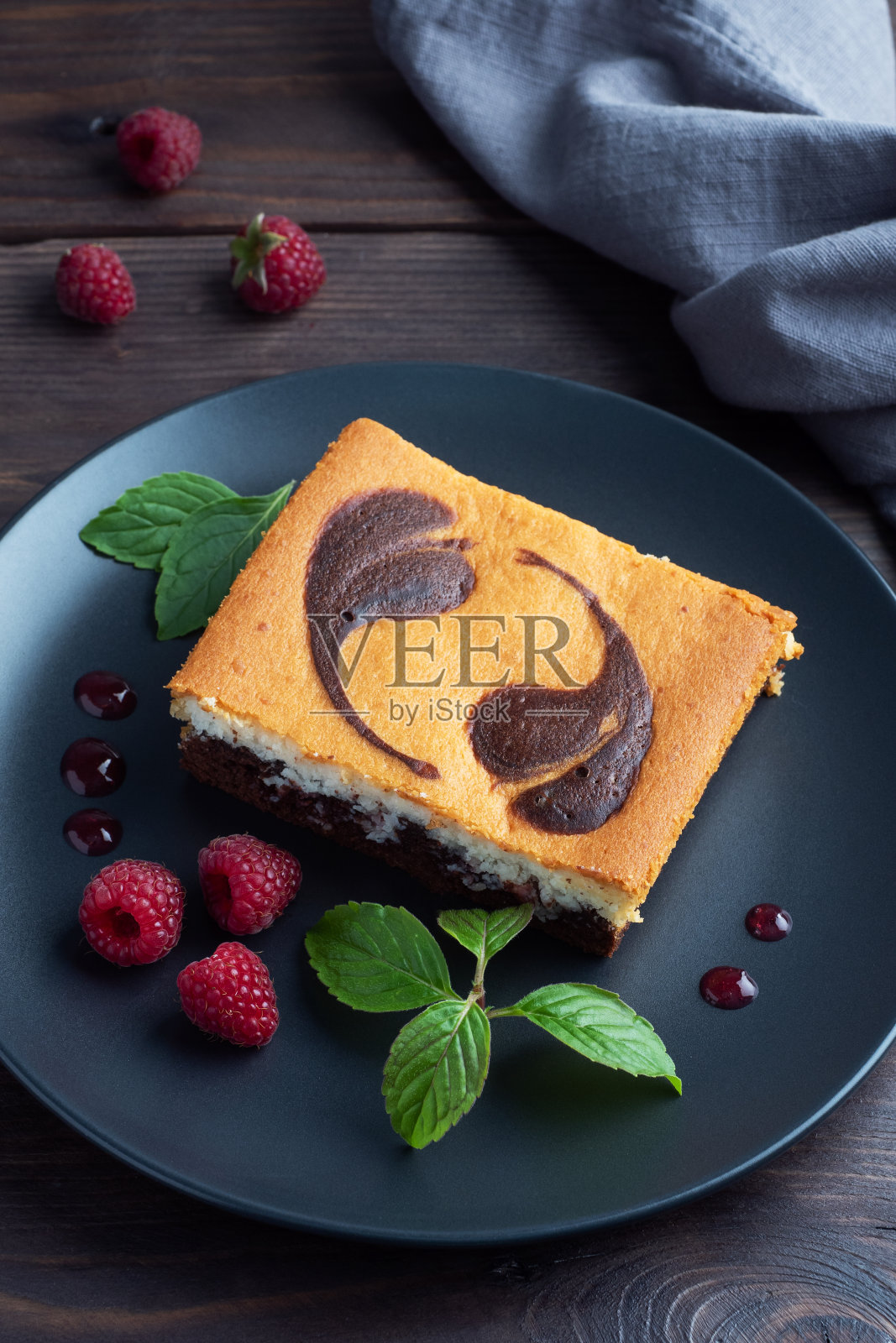 在一盘巧克力布朗尼和带覆盆子的凝乳芝士蛋糕上的双层蛋糕。深色背景拷贝空间照片摄影图片