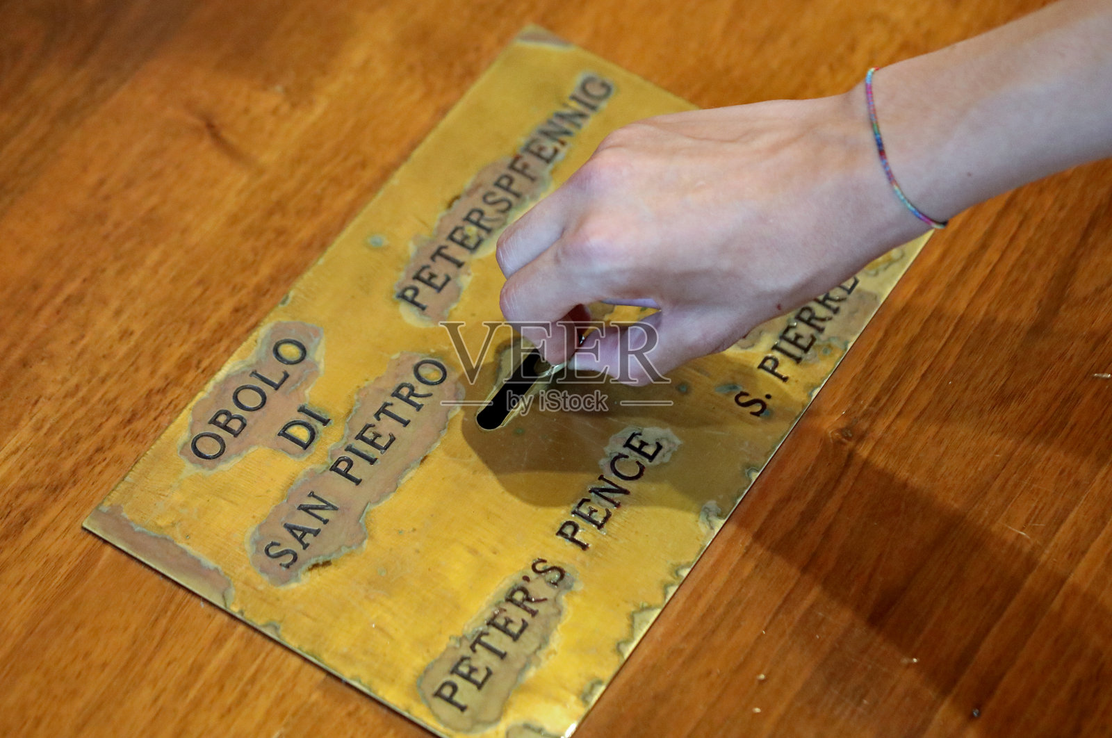 将一枚硬币放入教堂的祭品篮中照片摄影图片