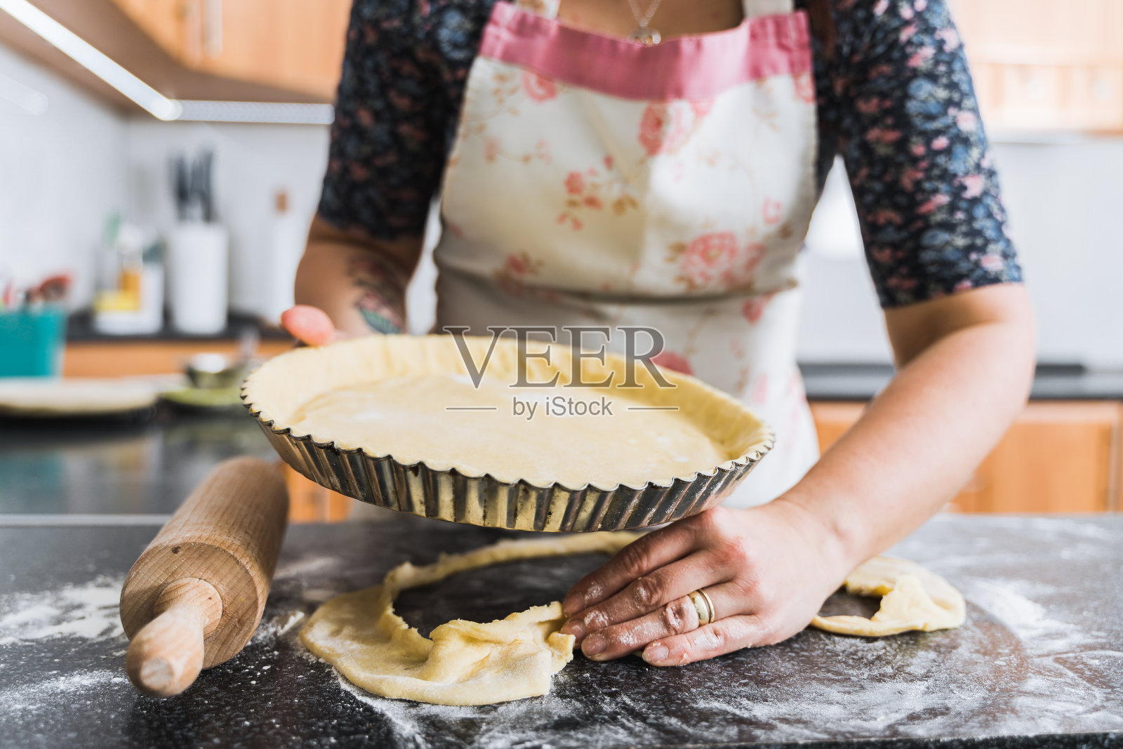 年轻的家庭主妇穿着围裙在家做苹果派。照片摄影图片