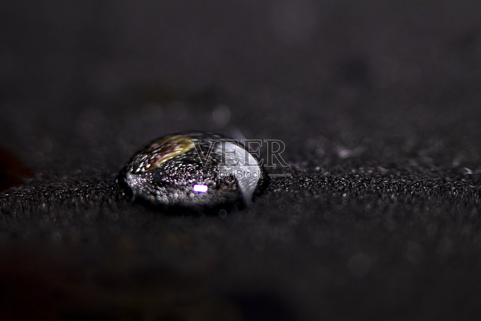 一滴水滴在黑色的表面上。带文本位置的侧视图。水疗中心的概念。有选择性的重点照片摄影图片