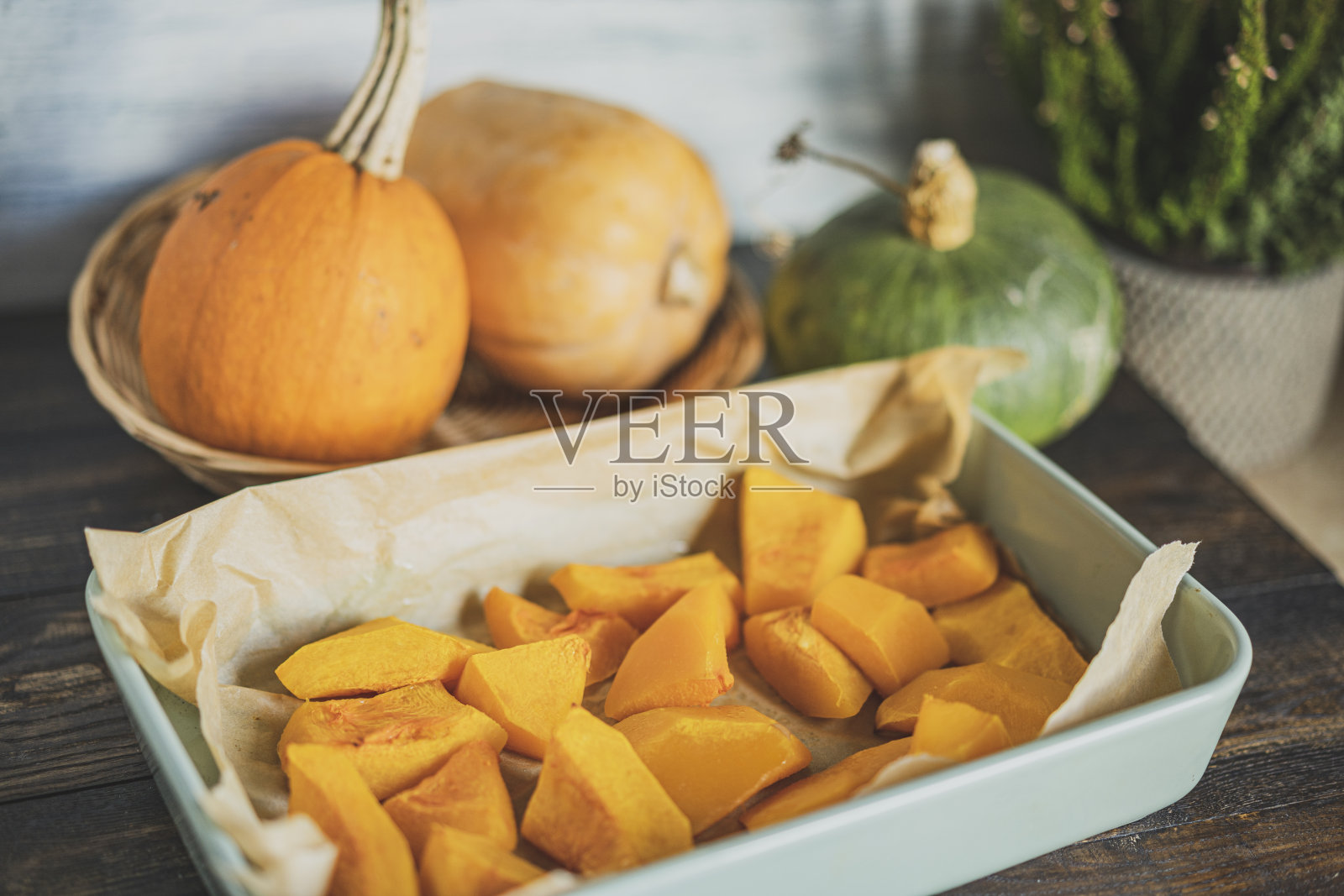 把烤南瓜切成小块放在烤盘里，配上不同的新鲜南瓜。照片摄影图片