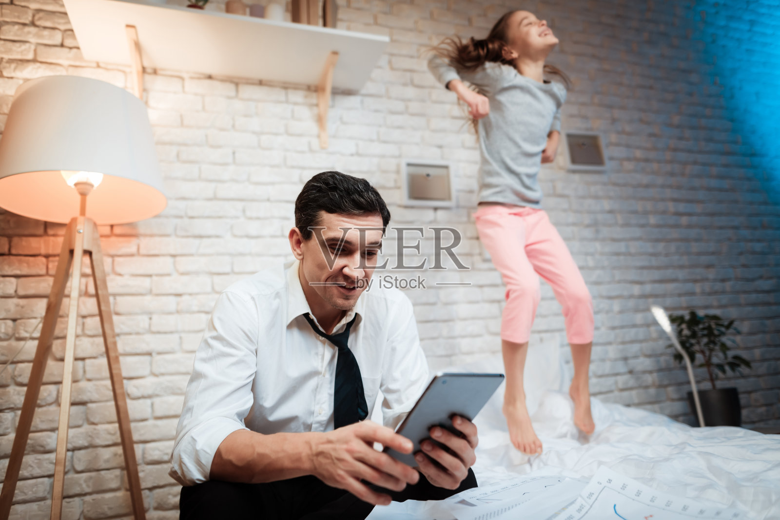 从事平板电脑的商人。小女孩不让她父亲工作。照片摄影图片