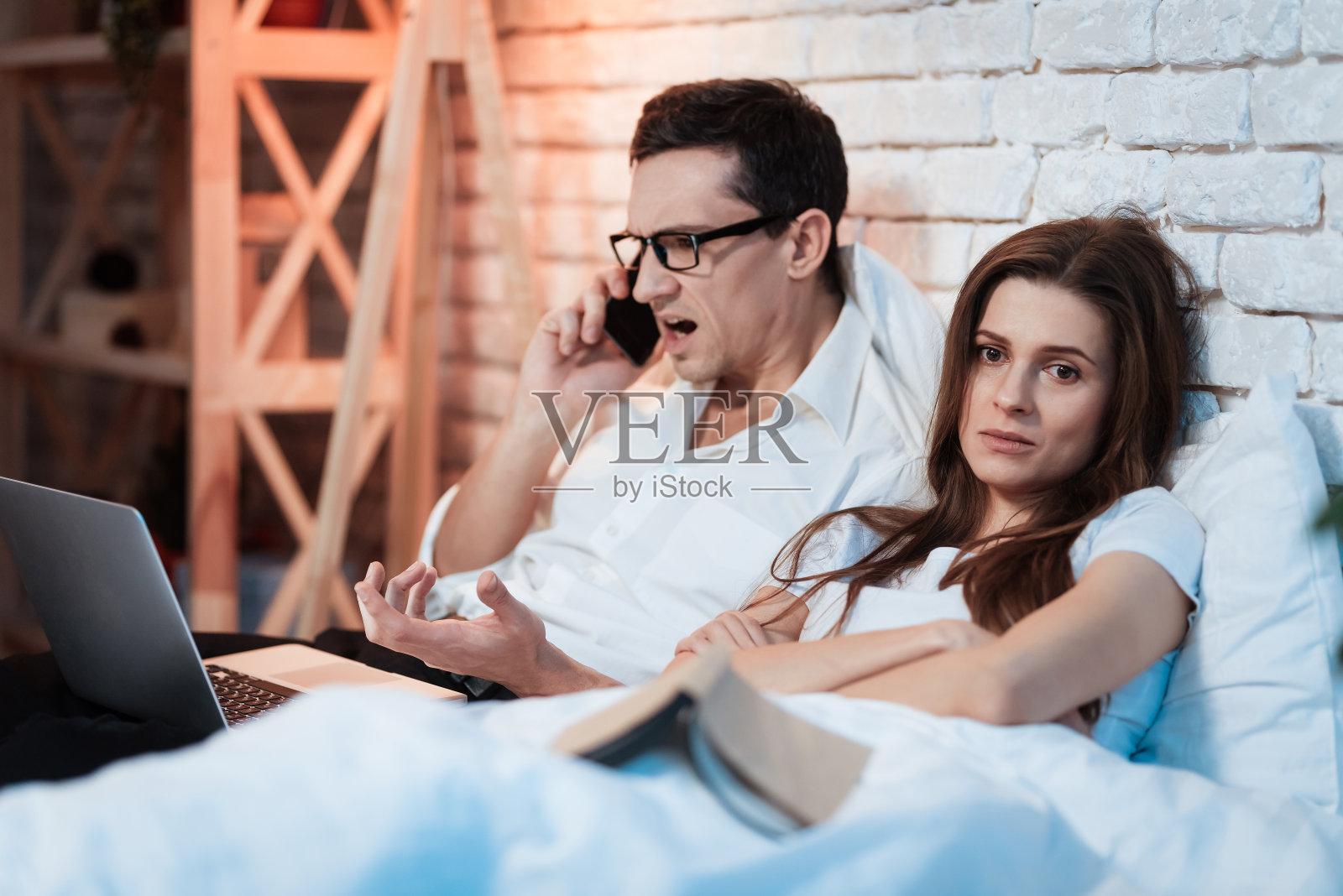 年轻的商人在笔记本电脑后面工作，在智能手机上尖叫。照片摄影图片