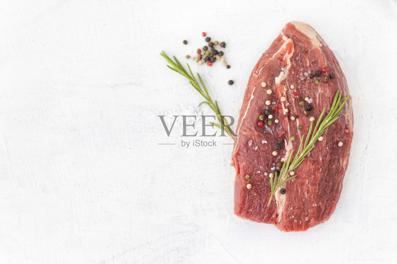 白石背景上放着香料的生牛肉。照片摄影图片