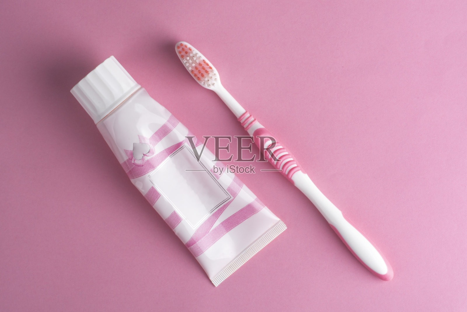 粉红色的牙刷和粉红色的牙膏管在粉红色的背景。照片摄影图片