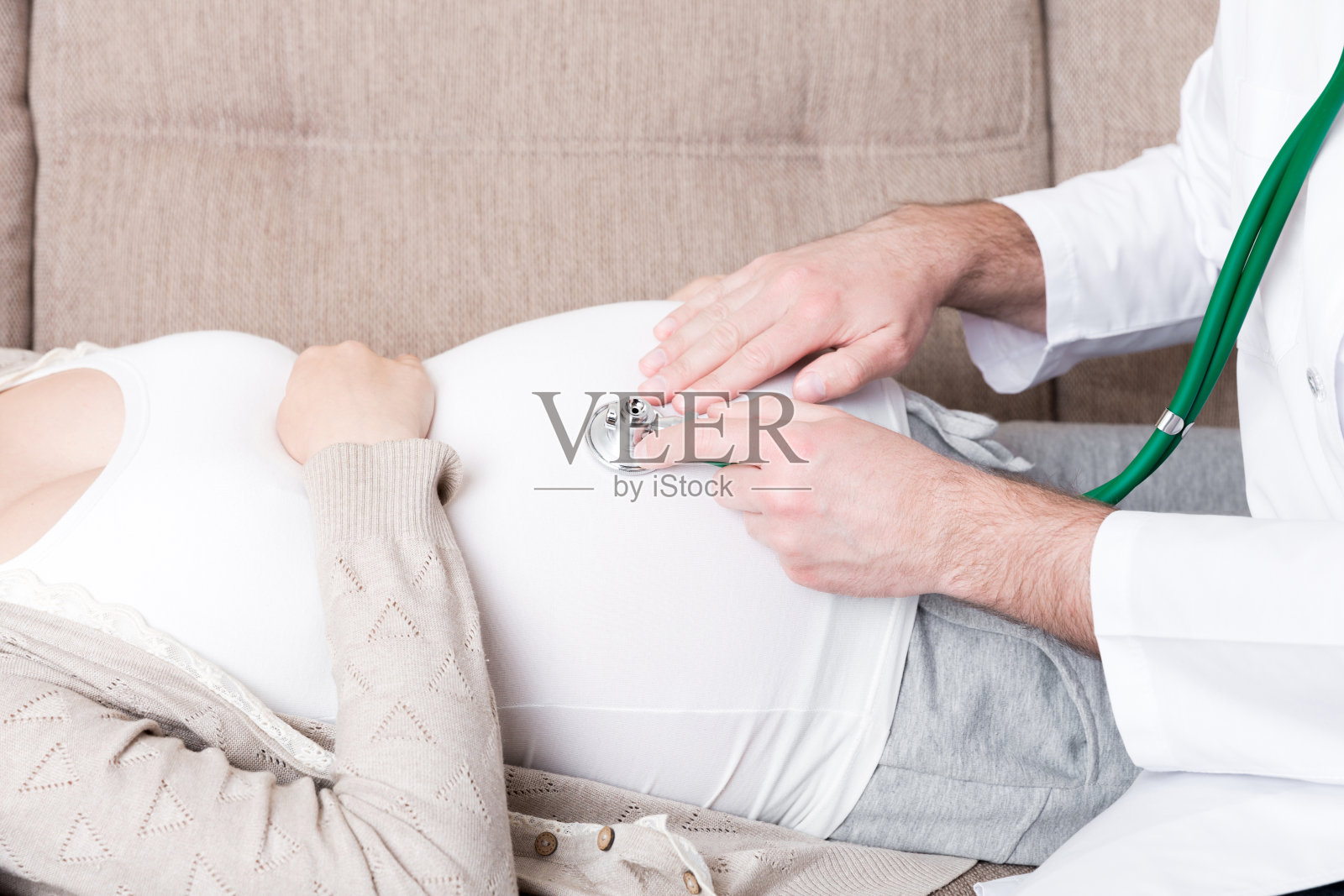 医生正在用听诊器检查孕妇的腹部。医生正在听一个婴儿的心跳照片摄影图片