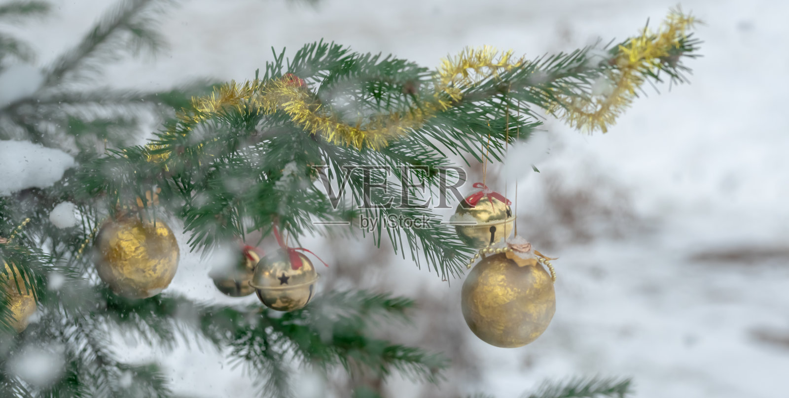 雪花中云杉树枝上的金色圣诞球照片摄影图片
