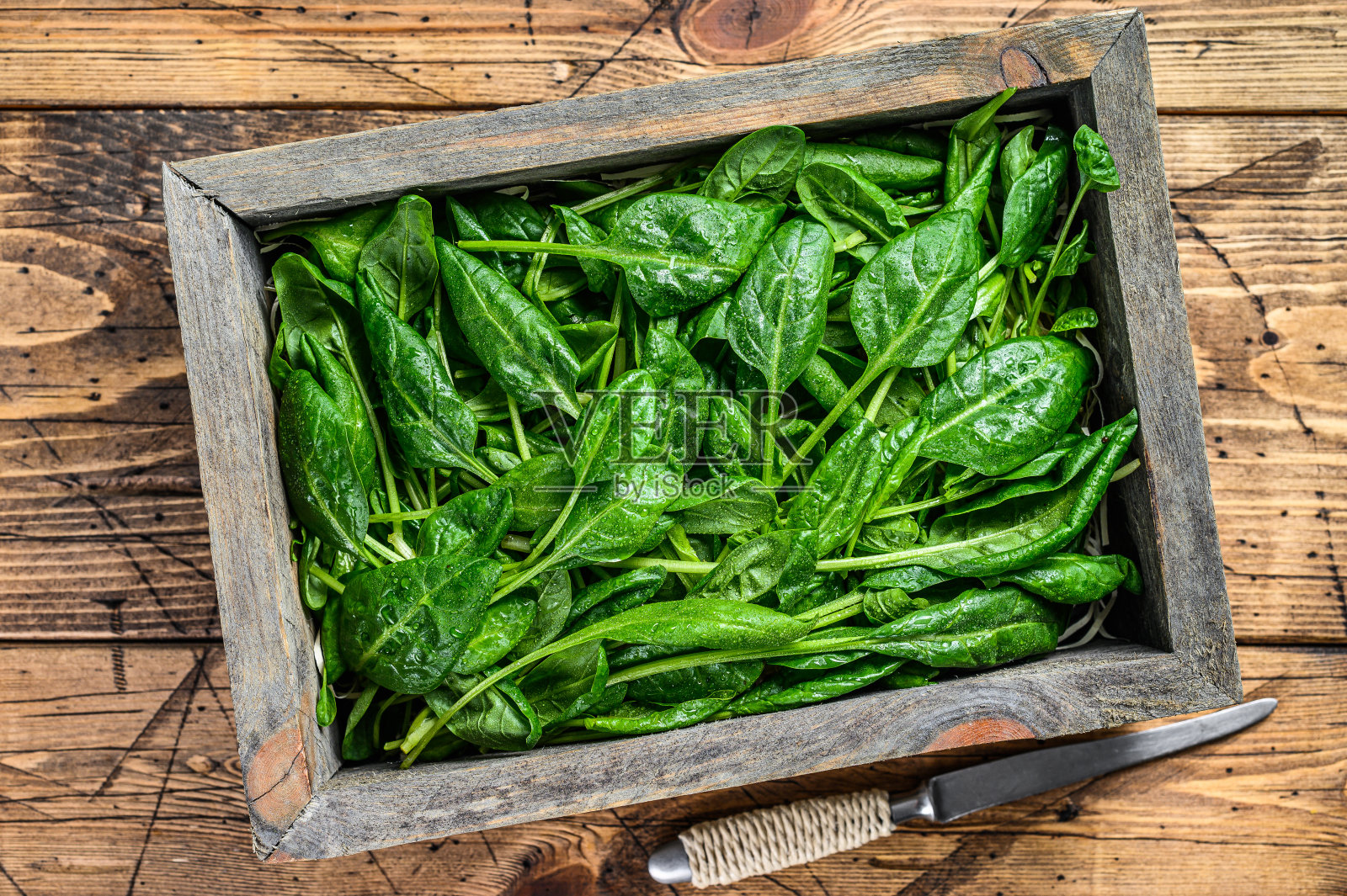 生菠菜叶装在木盒子里。天然木制背景。俯视图照片摄影图片
