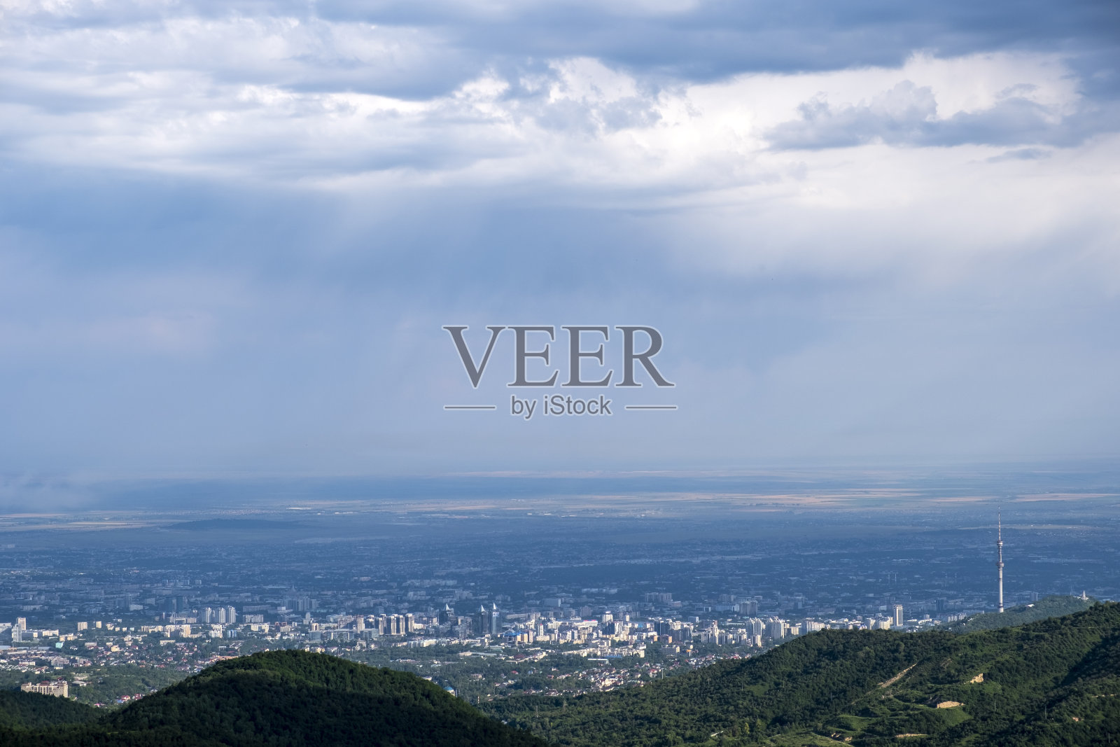 美丽的阿拉木图城市和山麓与风暴云捕捉的山区。碧绿的阿拉木图山麓云海，蔚蓝色背景，别有风味。照片摄影图片