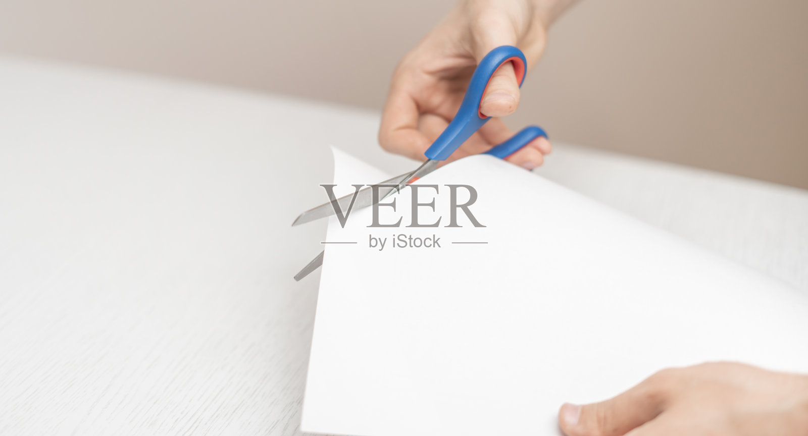 拿着一张纸的人的手用剪刀把它剪开照片摄影图片