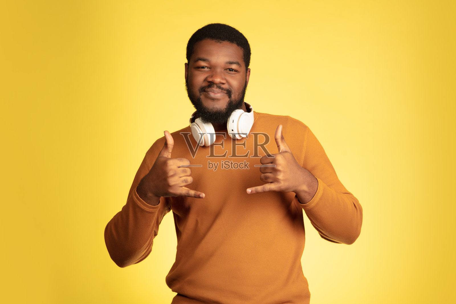 年轻的非洲裔美国人的肖像孤立在黄色的工作室背景，面部表情。漂亮的男性半长肖像与copyspace。照片摄影图片