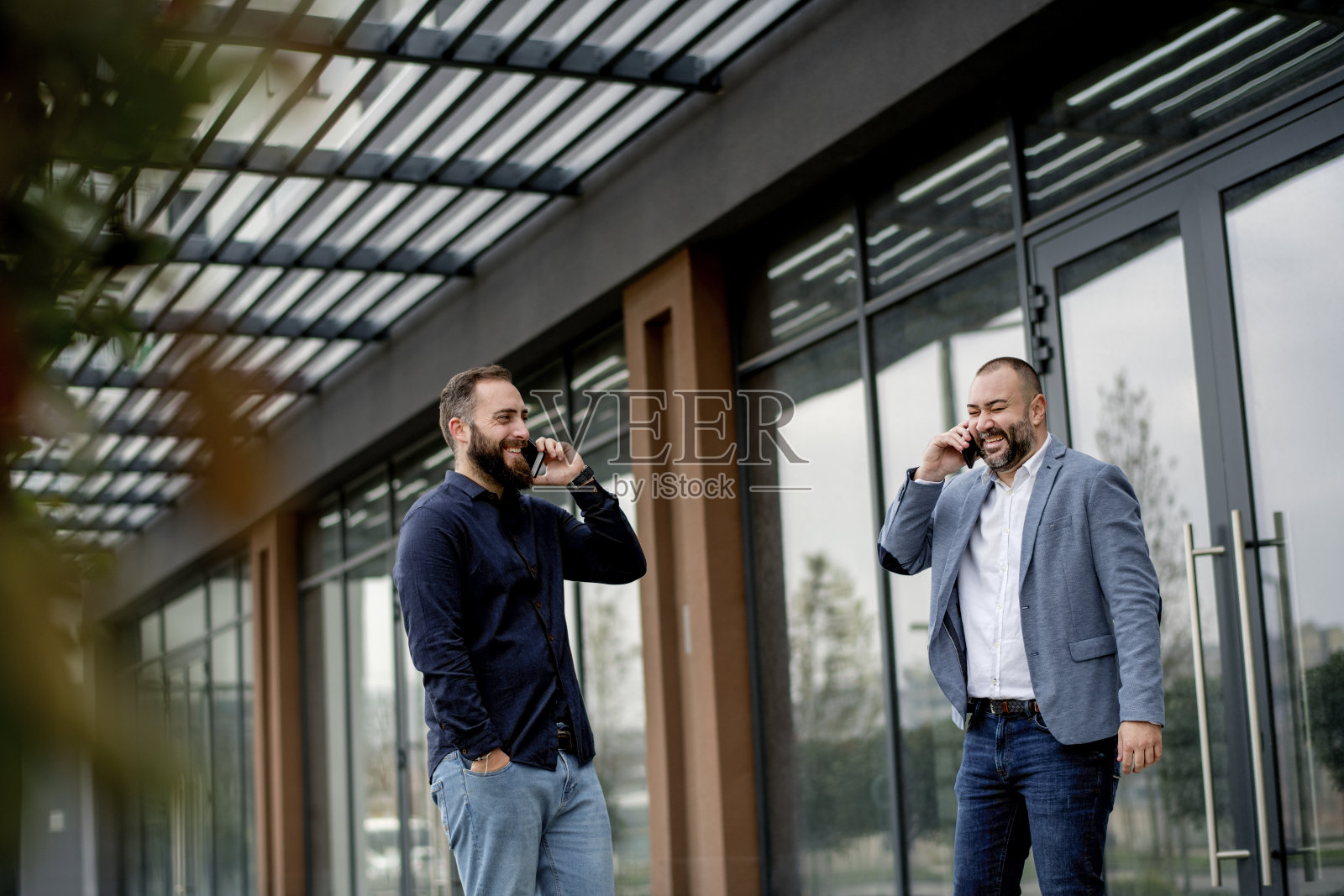 下班后，兴高采烈的商人同事们走在办公大楼前照片摄影图片