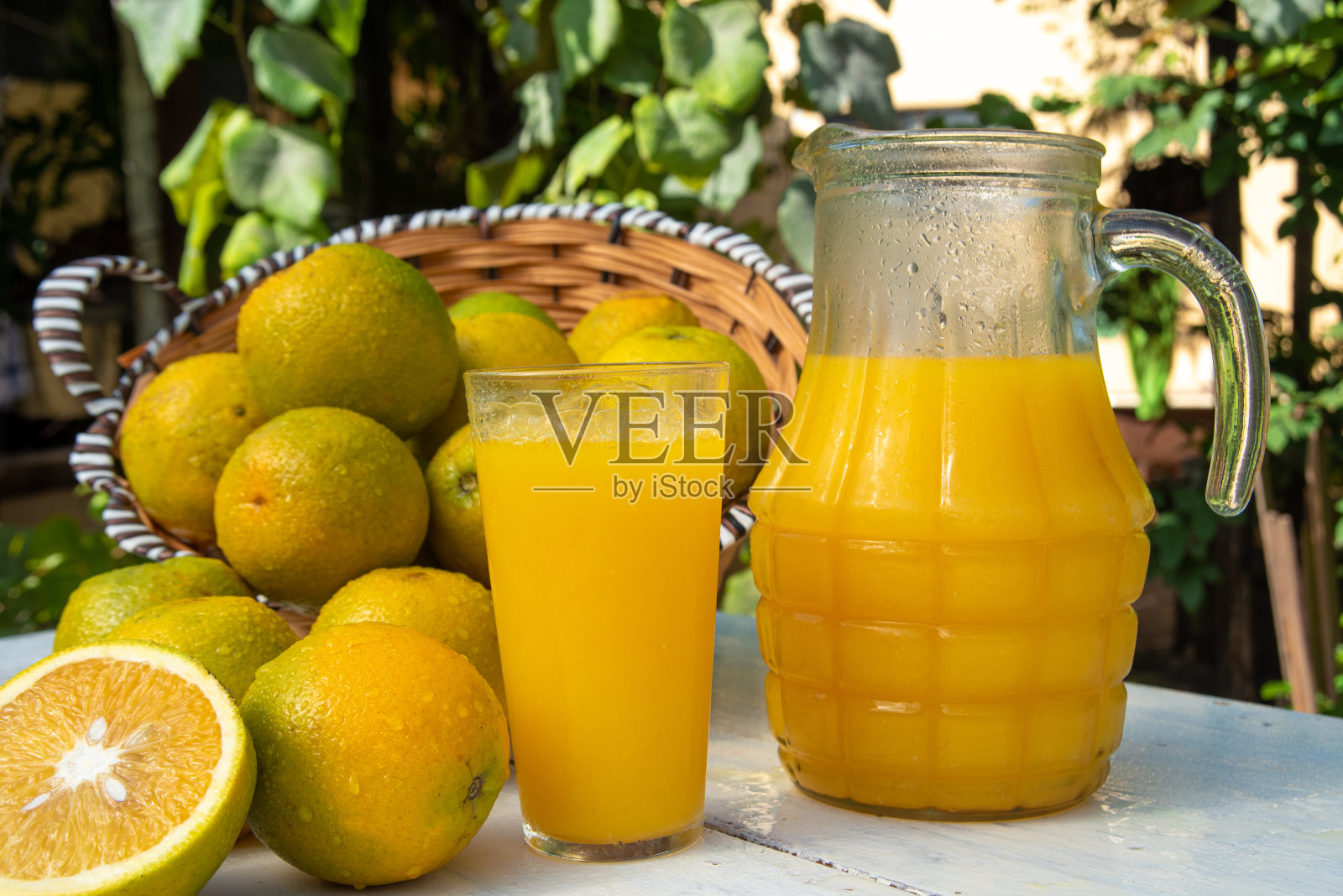 旧的白色桌子上放着橘子和橙汁，背景是模糊的自然，自然光，选择性聚焦。照片摄影图片