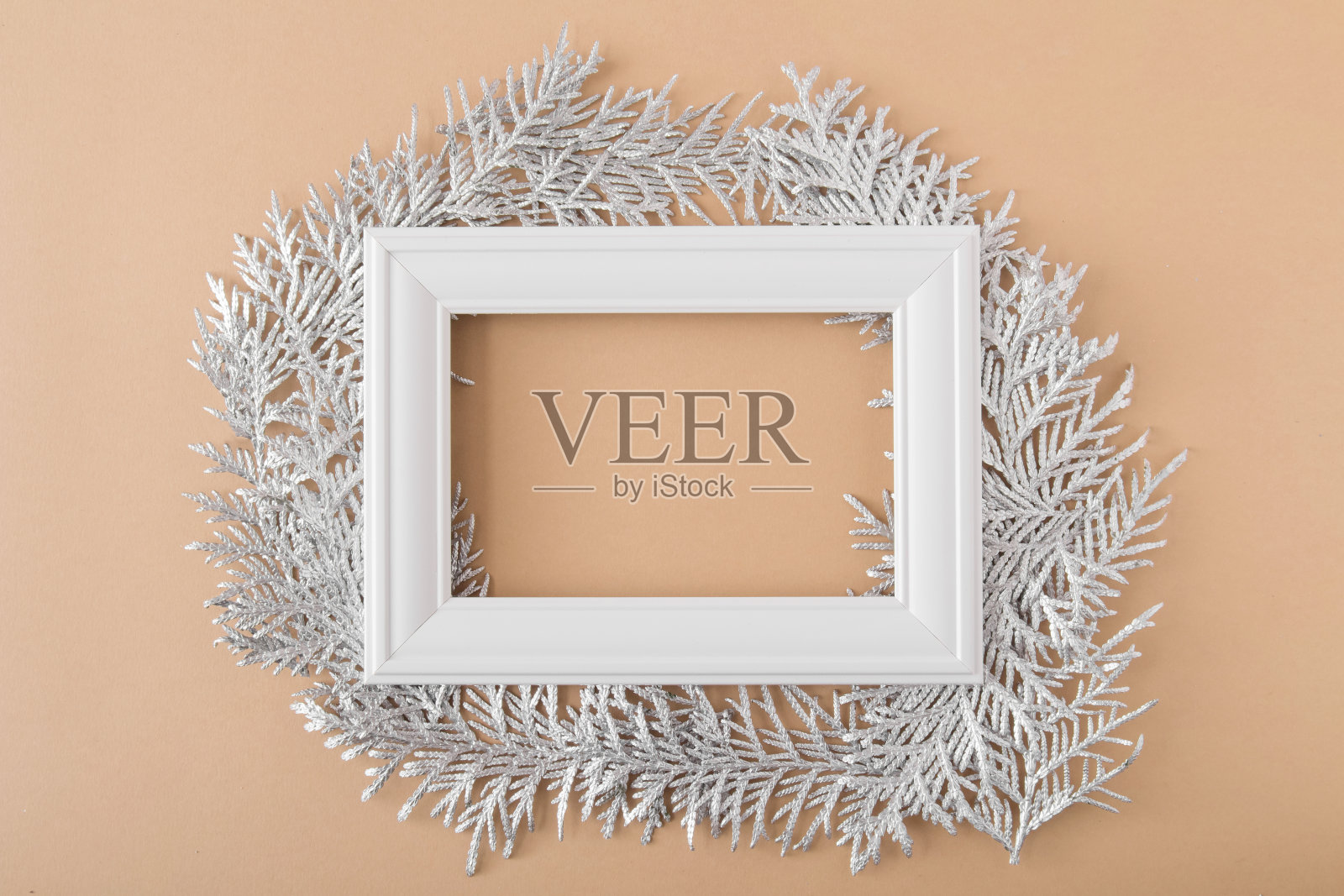 圣诞节的背景。白色的木框架躺在银白色的树枝上，浅棕色的背景。空间的文本。布局模型贺卡照片摄影图片