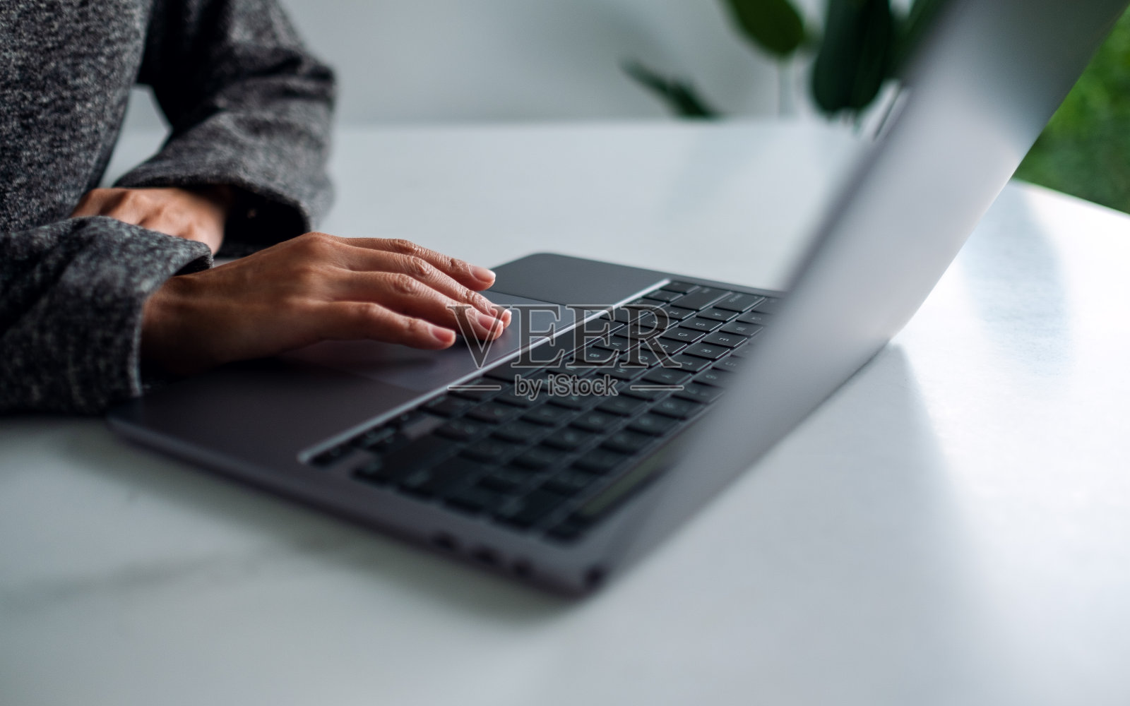 一位女士一边工作一边触摸桌子上的笔记本电脑触控板照片摄影图片