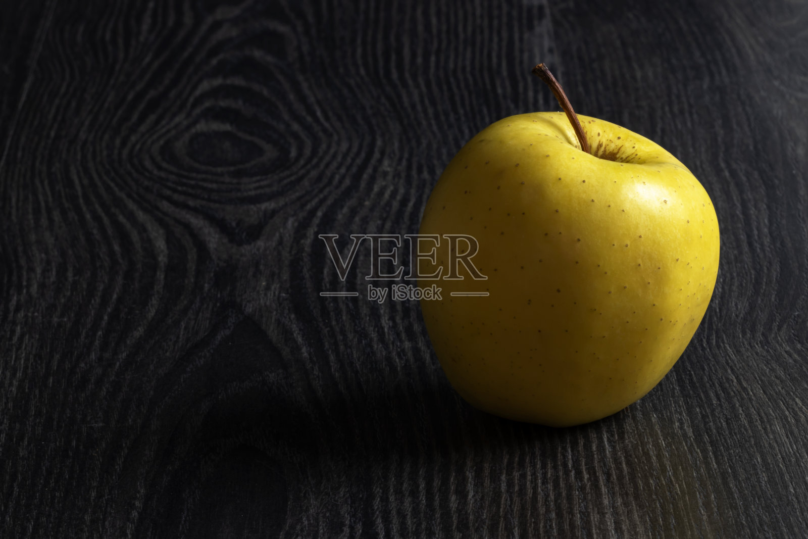 黑色背景和阴影上的金苹果照片摄影图片