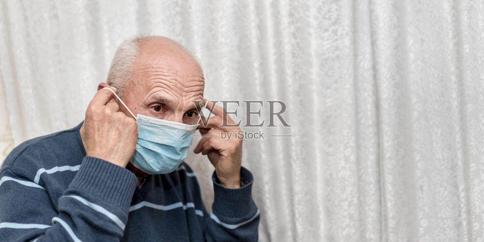 成熟男性尝试健康安全防护口罩白色窗帘背景照片摄影图片