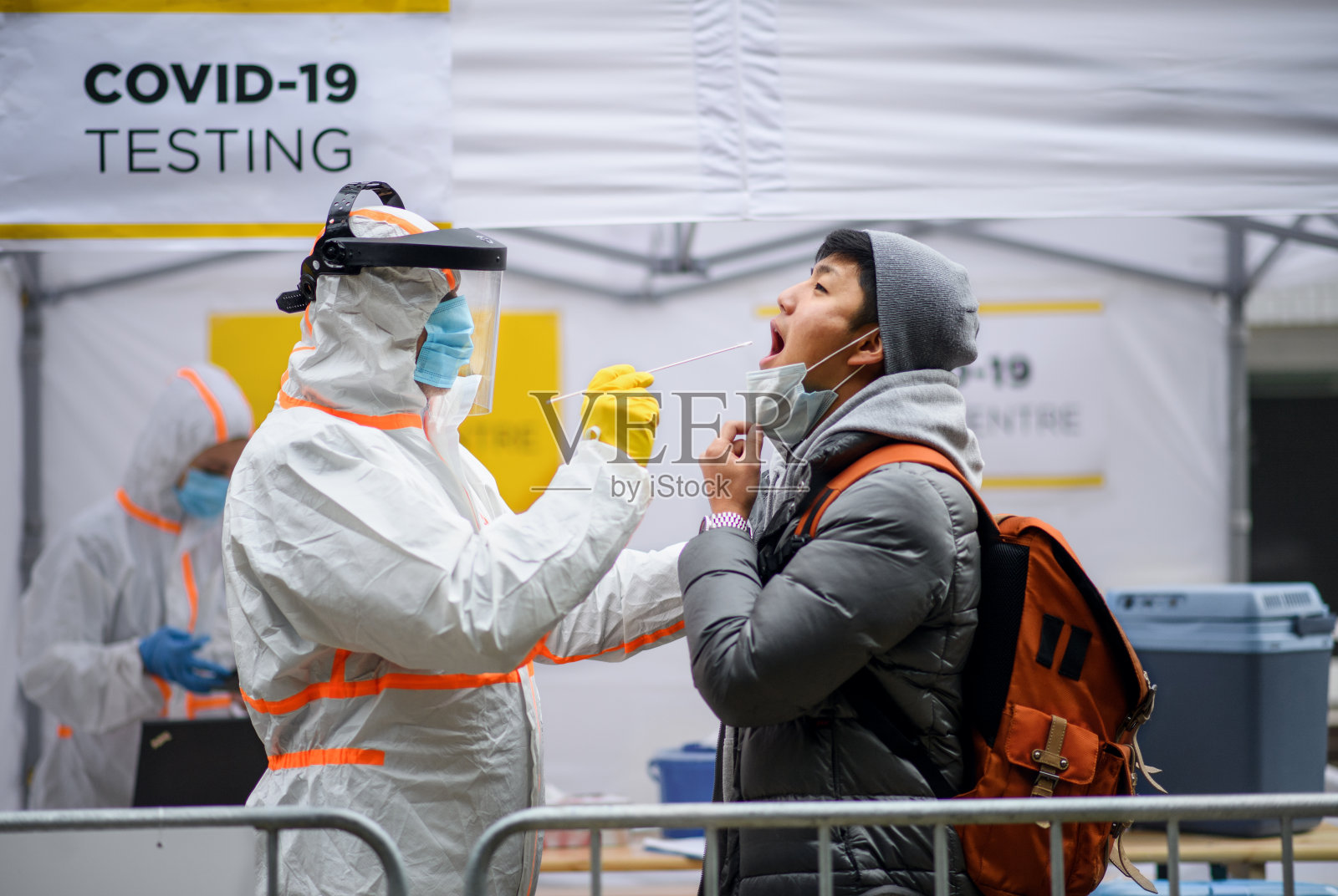 青年男子在街头covid-19检测中心户外，接受冠状病毒和拭子的概念。照片摄影图片