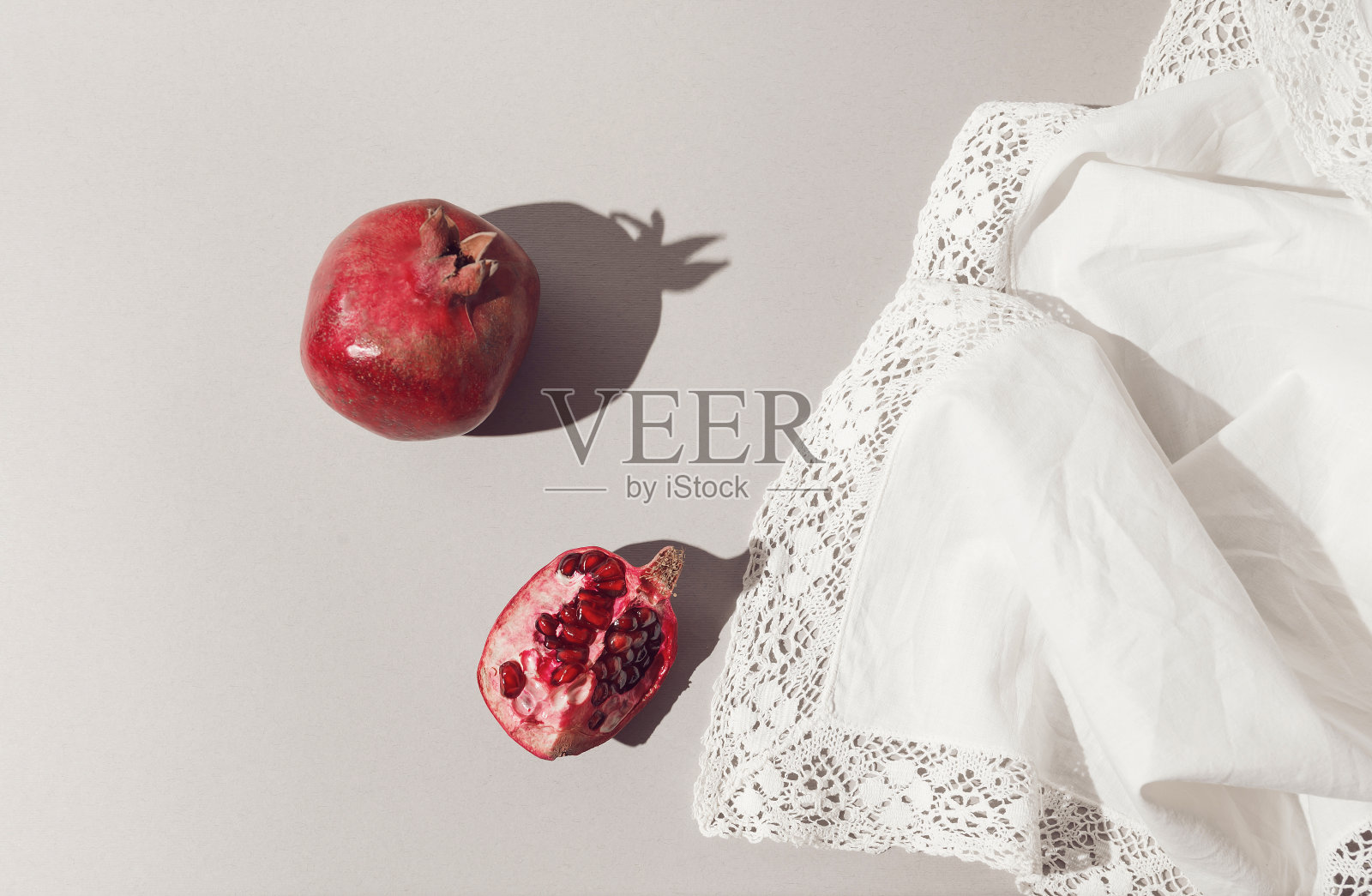 新鲜的石榴在轻白色织物背景。照片摄影图片