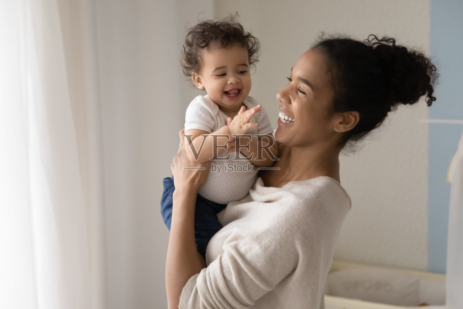 微笑的混血儿妈妈和蹒跚学步的婴儿玩照片摄影图片