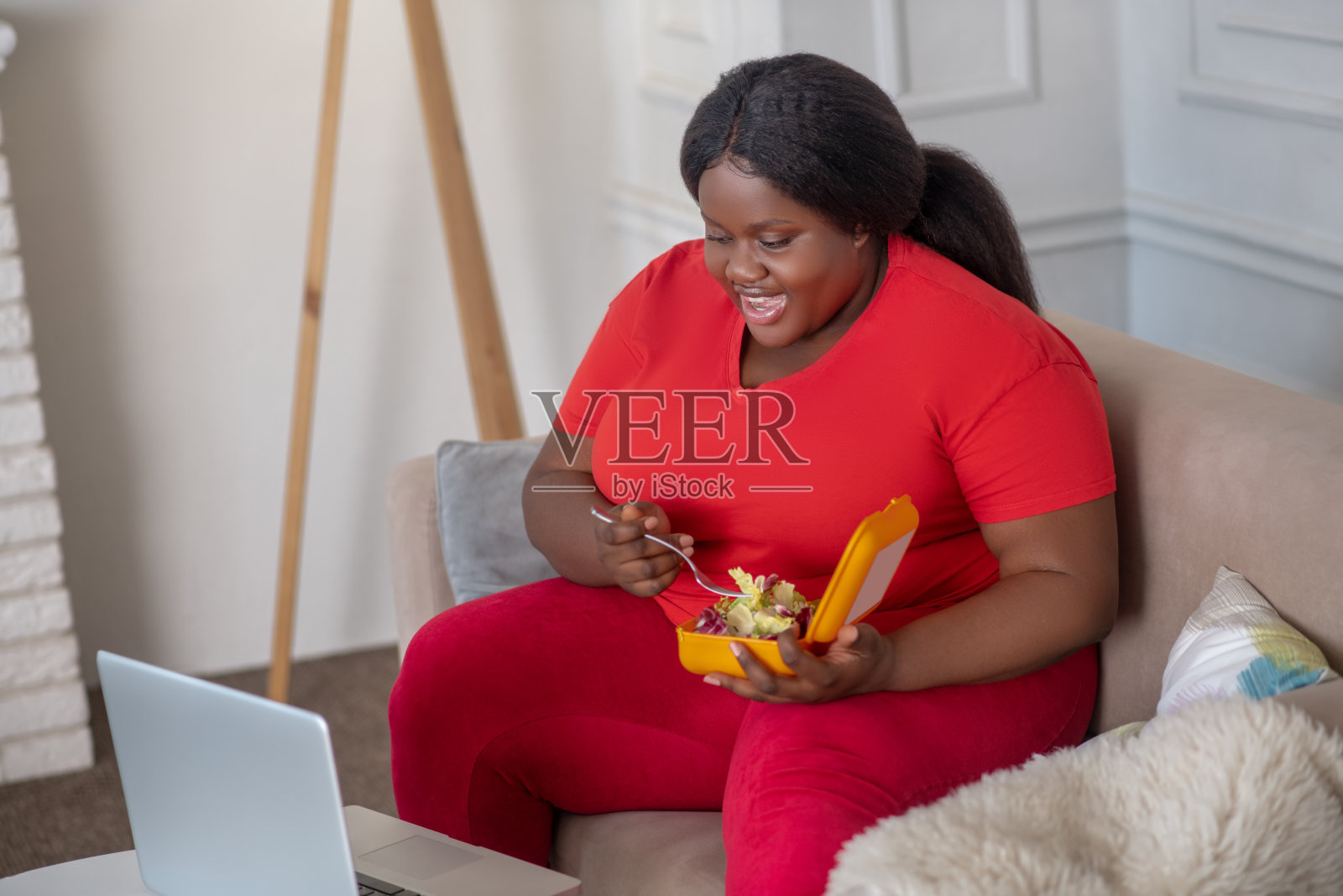 大码的非裔美国女人一边看一边吃照片摄影图片